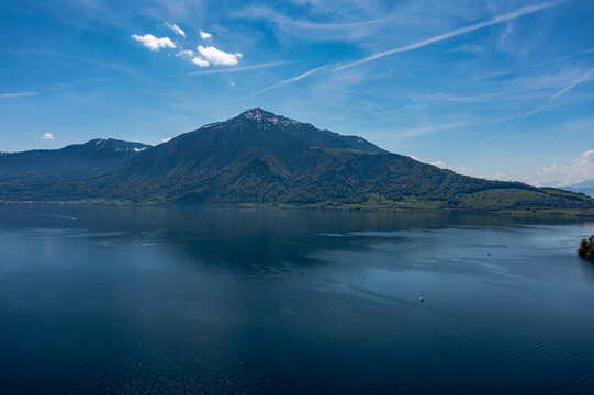 Aerial panoramic view of Lake Zug with forested mountain and calm reflective water - Central Switzerland