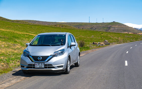 Silver car on winding road through grassy hills