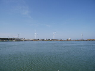 Calm ocean with distant wind turbines under clear sky, Japan © Shizuki