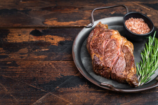 Seared beef chuck eye steak in metal pan with rosemary and salt. Tender cooked beef meat top view.