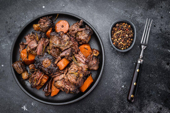 Homemade beef and lamb oxtail ragout in skillet, gelatin rich slow cooked meat with vegetables, overhead food photography
