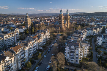 Naklejka premium European cityscape with historic cathedral and residential buildings under clear sky, peaceful urban environment with tree lined streets and distant hills creating serene atmosphere