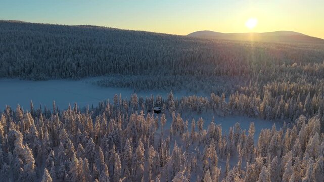 Vast snow-covered forests and serene frozen landscapes define Akaslompolo. Witness the breathtaking beauty of Lapland as the sun rises over tranquil winter scenery, creating a magical atmosphere.