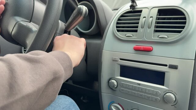 Close-up view of a driver turning the ignition key to start a car engine inside the vehicle.