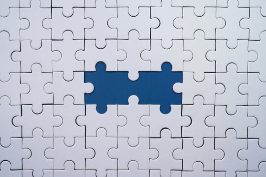 Incomplete white jigsaw puzzle with two significant missing blue pieces