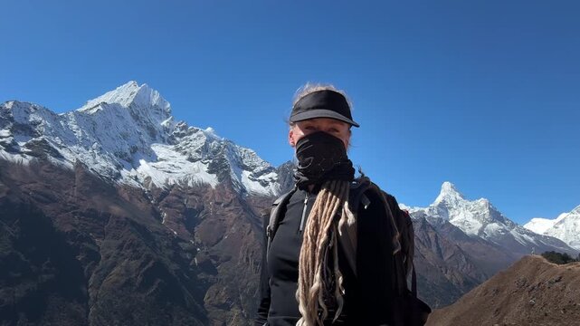 Female trekker with backpack and dreadlocks records selfie video in Namche Bazaar area on the way to Everest Base Camp, Himalayan mountains, Nepal, high altitude trekking route