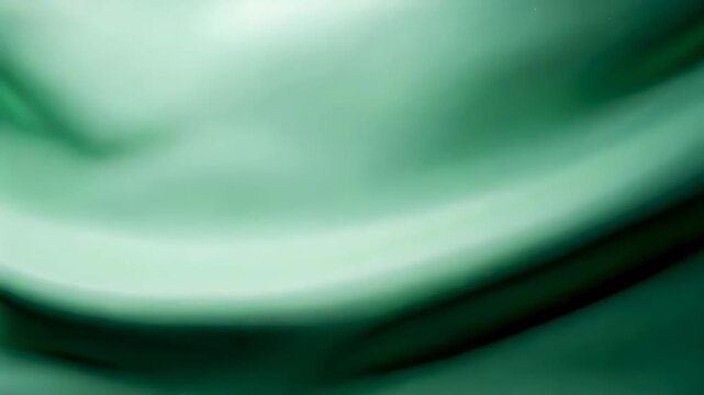Green silk fabric flowing with elegant waves. Smooth satin cloth background showing luxury textile texture. Glamorous drapery folds for fashion and design concept.