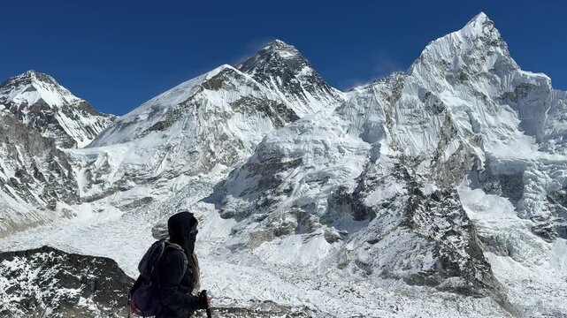 Woman hiking on Kala Patthar with Mount Everest in background, Nepal. Stunning Himalayan panorama, sunny day, trekking adventure, travel lifestyle, freedom, exploration, slow motion