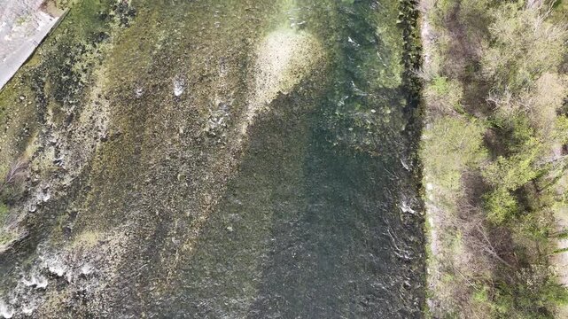 Top down aerial view of clear river water and rocky shoreline