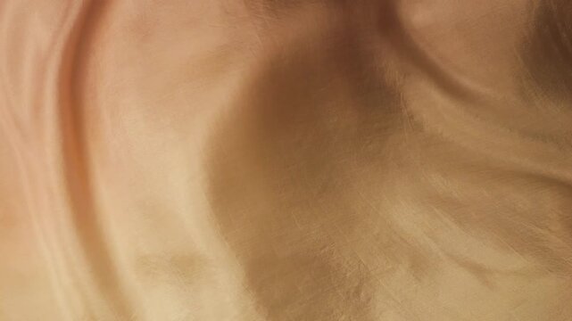 Abstract background of natural silk fabric waving in the wind. Soft beige and brown waves of flowing material. Close up of smooth textile texture with elegant motion. 
