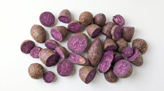 Top view flat lay of fresh raw ube (purple yams) scattered on white background
