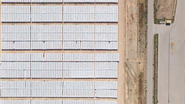 A stunning, top-down aerial drone shot captures a sprawling intermodal logistics terminal, dominated by immense, perfectly ordered rows of white shipping containers. 