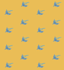 Fototapeta premium Cute blue sharks swimming in a repeating pattern on a warm yellow background