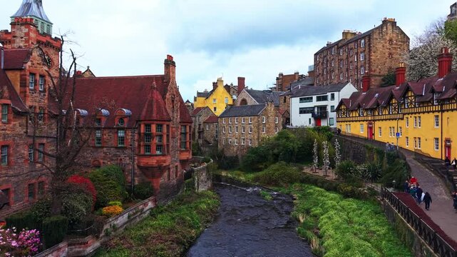 Atmospheric aerial tracking shot of historic stone houses along the river in Scotland.