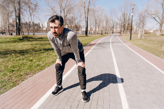 Exhausted runner resting after jogging workout in park
