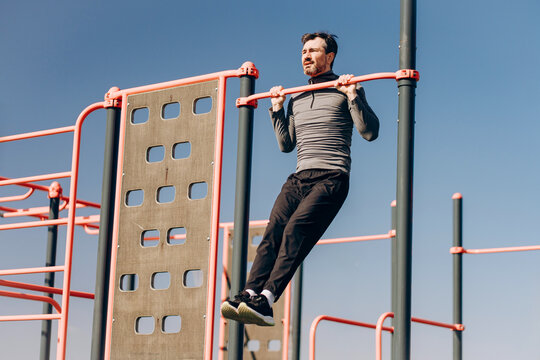 Man doing pull ups on horizontal bar at outdoor gym