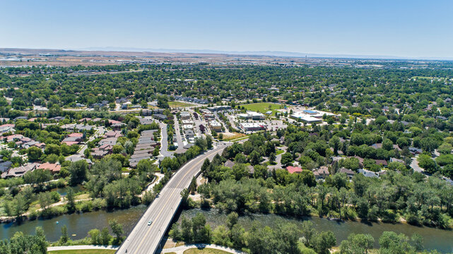 Aerial View of Highway Bridge Crossing River Through Lush Green Suburban Neighborhoods in Summer