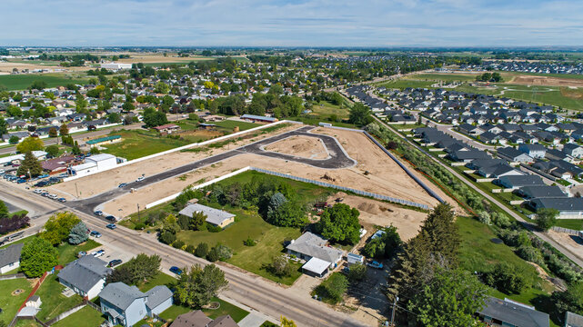 Aerial View of New Residential Subdivision Under Construction Adjacent to Established Suburban Neighborhood in Summer