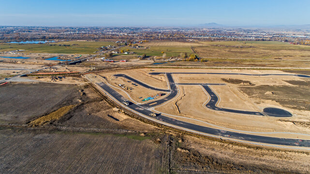 Aerial View of New Subdivision Road Infrastructure Under Construction with Curved Streets and Graded Lots on Flat Plains