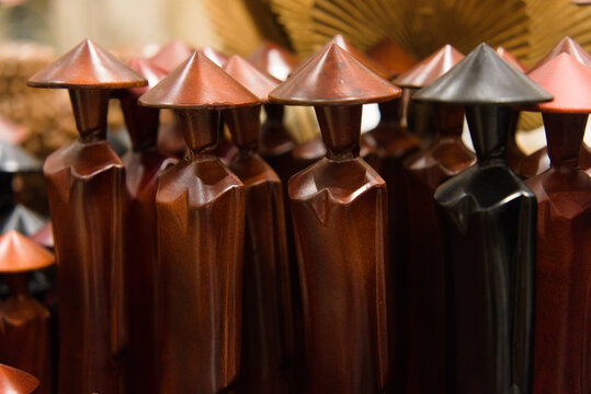 Row of traditional Vietnamese wooden figurines wearing conical hats (Non La), handmade souvenirs in a craft shop