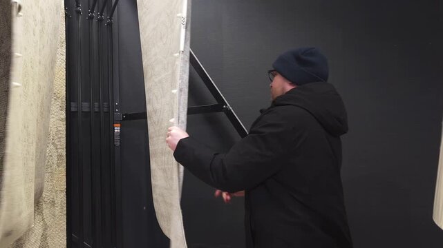 A man choosing / buying a carpet in a store mall shop