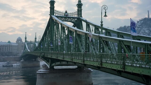 Budapest Liberty Bridge in Winter with Snow Overlooking Danube River and Gellert Hill at Sunset, Panoramic View of Historic Green Metal Architecture