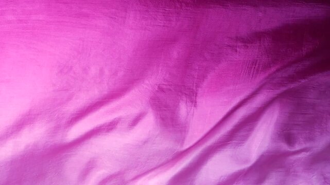 Abstract silk texture with soft waves. Natural purple silk fabric blowing in the wind. Smooth flowing material creating magenta background. Elegant textile with luxury satin ripples.