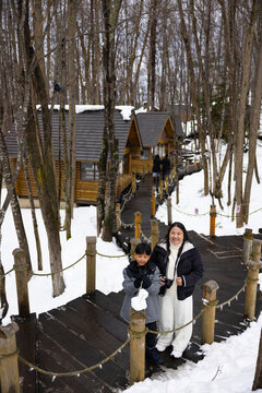 Asian mother and son travel. Traditional village. asian fat mother and family tourist Visiting in Furano, Traveler in Sweater sightseeing Ningle Terrace Cottages. landmark for attractions in Hokkaido