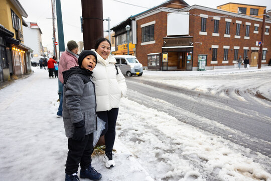 Family travel and Vacation together, Asian mother and son Traveler on Sidewalk with Cityscape Background. street. Boy Enjoying Sunny Winter Day in Picturesque Town. child posture suggests curiosity