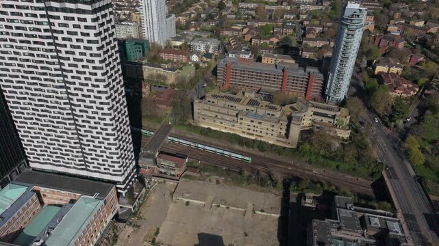 Public trains arriving at Croydon train station between modern skyscrapers. Aerial circular motion above railway tracks with trains in city center.