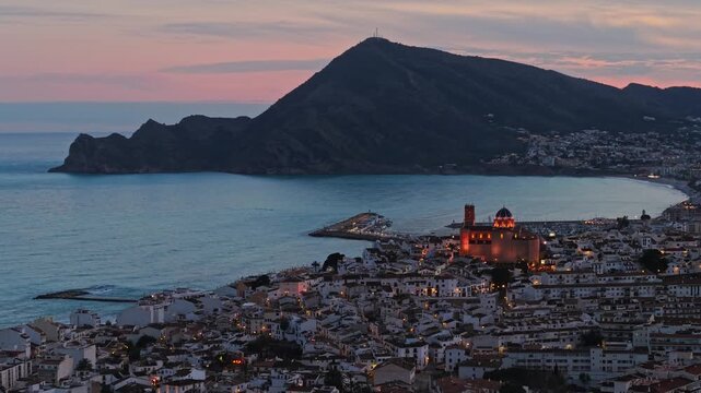 Aerial video frame of Altea at twilight with illuminated church, marina and coastal bay, Alicante, Spain