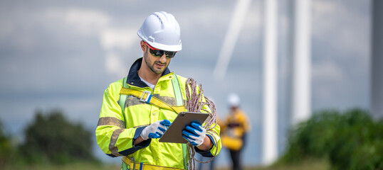 Fototapeta premium Male man engineer inspection by tablet gesture check control wind power machine out door wind energy factory. technician professional worker check wind power machine turbine field inspection