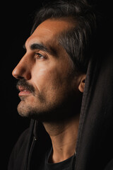 Fototapeta premium Man in dark hoodie gazes thoughtfully into the distance