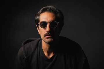Obraz premium Mysterious man in sunglasses captures intrigue in shadowy setting