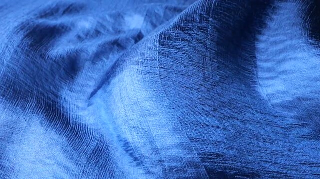 Blue natural silk fabric waving in the wind. Abstract waves and ripples on smooth textile background. Elegant texture of shiny material with linear pattern. Soft motion of luxury fabric.