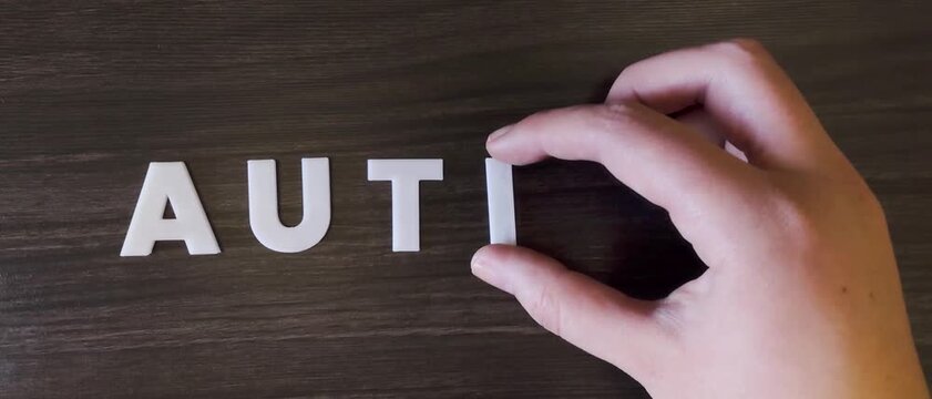 the word autism written on a dark background with white block letters or capital letters (fast version)