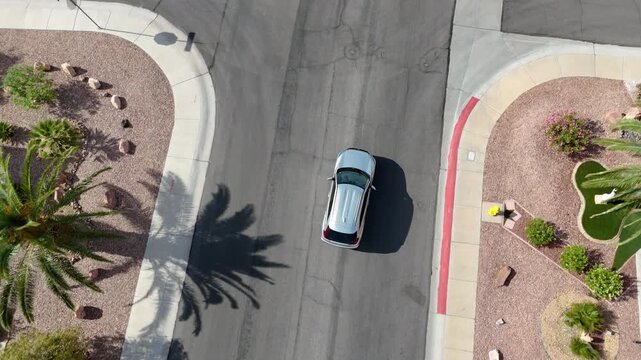 Aerial view of a silver SUV driving through a southwestern suburban neighborhood and pulling into a driveway