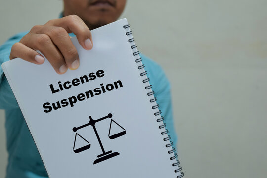 Businessman holds in hands a book with the name of the license suspension.