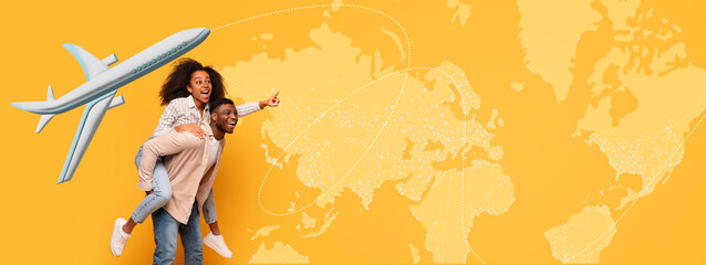 A couple stands in front of a large world map. The man carries the woman on his back. They smile and point at various locations. An airplane graphic is included, adding to the theme of travel. © Prostock-studio