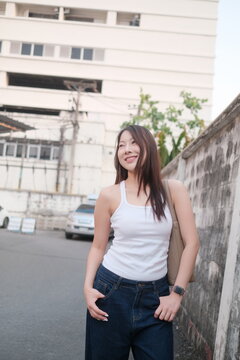 Young woman smiles casually, leaning against a wall