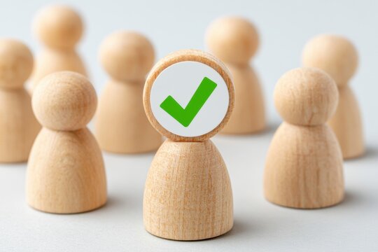 Multiple wooden figures with one selected figure featuring a green check mark symbol, representing choice or approval in a minimalistic setting