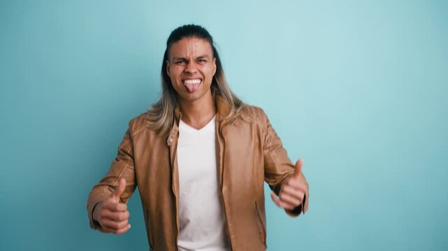 Handsome latino man with long hair dancing and having fun in a studio. The expressive model is celebrating a victory with excitement