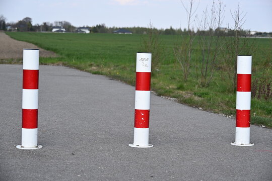 Red and White Road Delineator Posts with Green Field in Background
