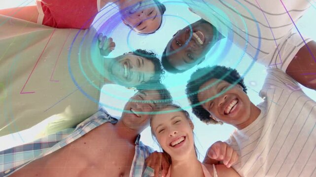 Six adults leaning over low camera, creating social content while colorful rings pulsing, smiling
