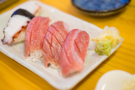 Close up of otoro fatty tuna nigiri on a rice pillow served with squid sushi with subtle shine, Japanese luxury sushi concept for fine dining