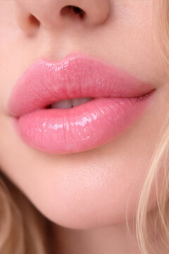 Macro close up of woman lips with pink lipstick and glossy texture