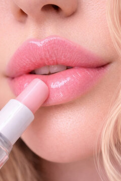 Applying pink lip gloss with applicator macro close up beauty concept
