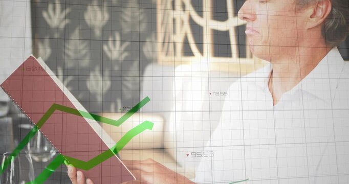 Mature man sitting at cafe holding red tablet, tapping screen prompted by animated financial charts