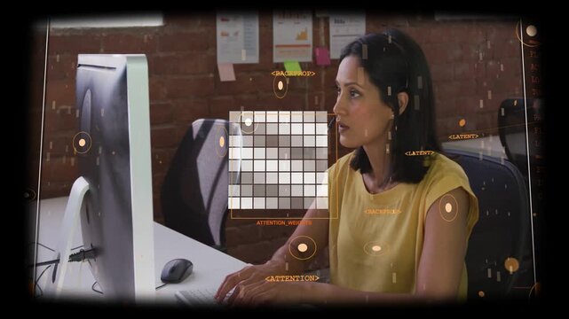 Mature Asian woman typing on keyboard at desk wearing yellow top monitor showing orange overlay