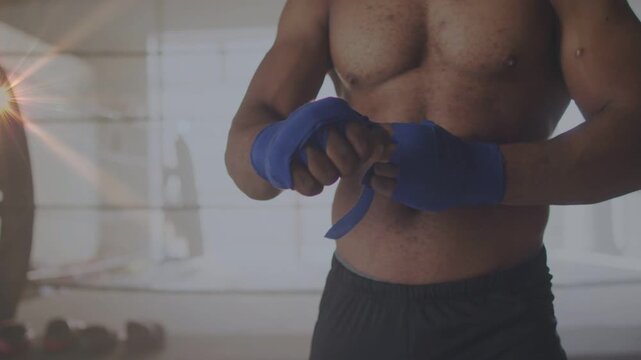 Male boxer threading blue hand wrap through thumb, winding and tucking, preparing hands for boxing
